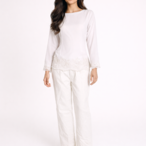 South Asian model wearing an ivory lace-trim blouse with wide-leg trousers and pearl-detail heels against an off-white cyclorama backdrop.